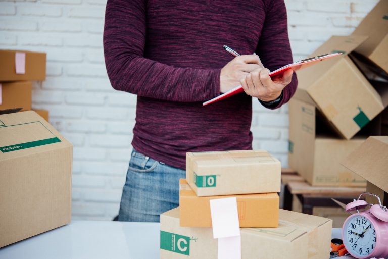 Handsome Young man working with papers among parcels at table in